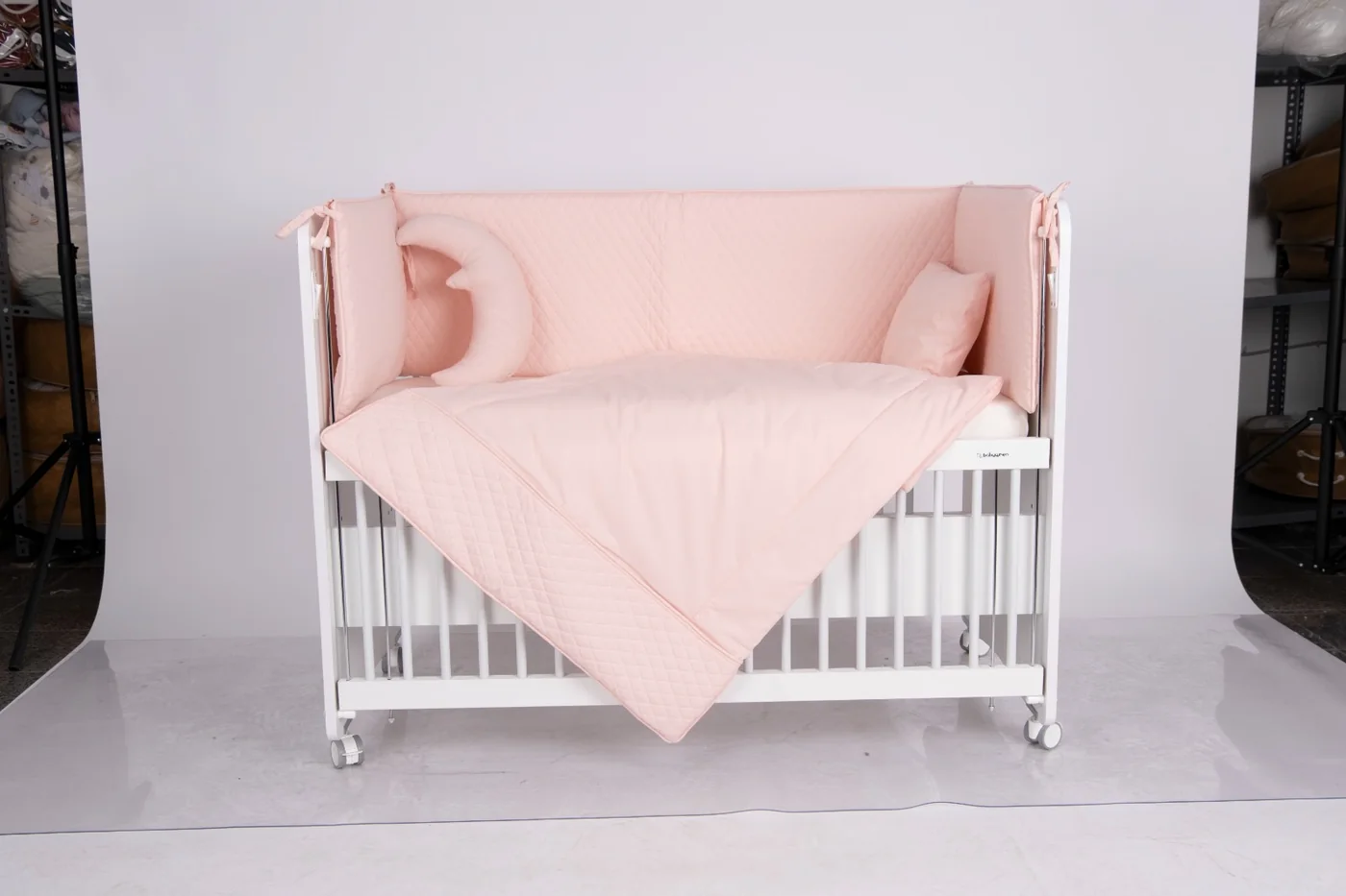 Blush quilted crib bedding with moon cushion
