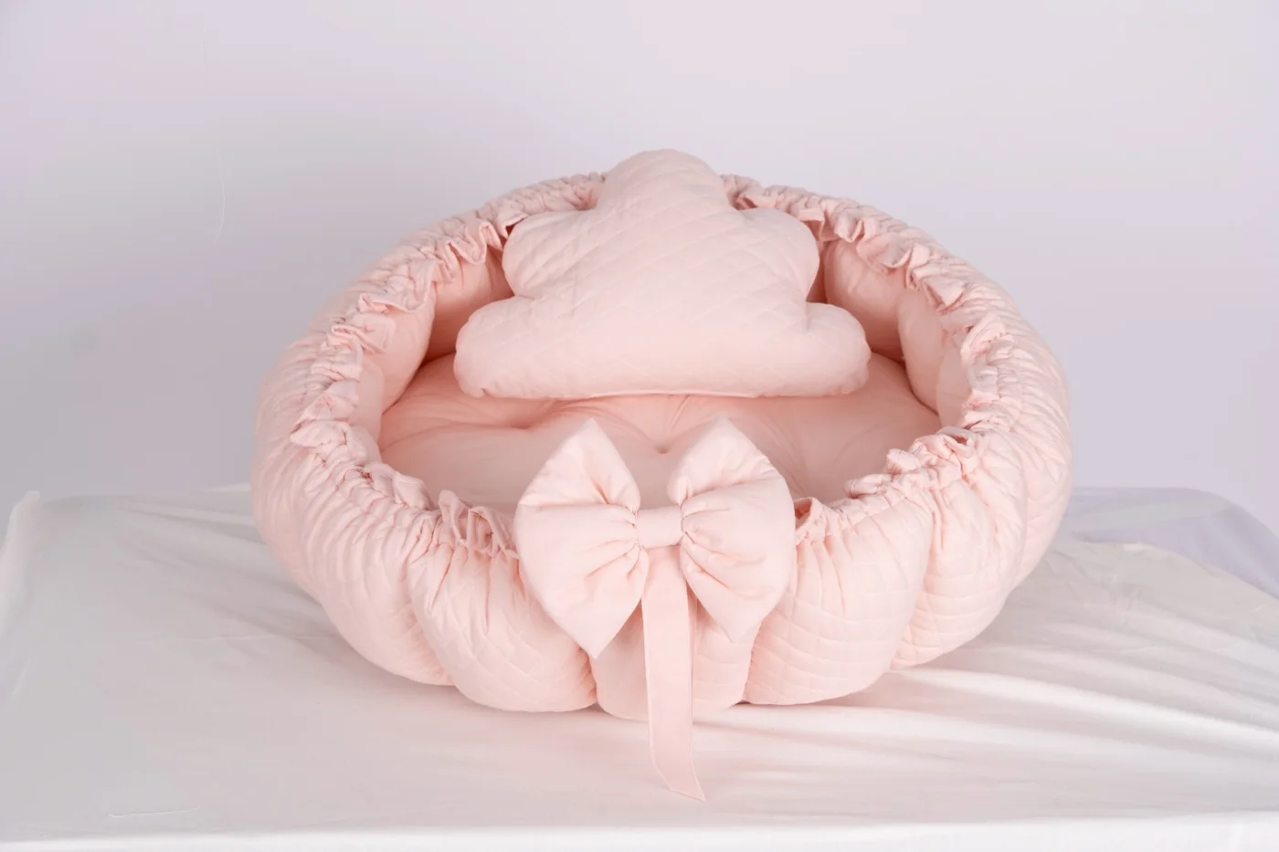 Round blush quilted baby nest with cloud cushion and bow